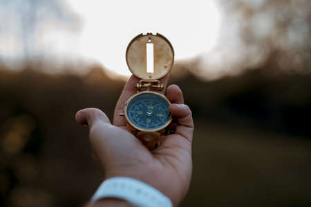 A closeup shot of a person holding a compass with a blurred backgroundの写真素材