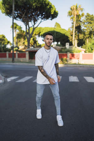 A vertical shot of an athletic young man with tattoos posing standing on the streetの写真素材