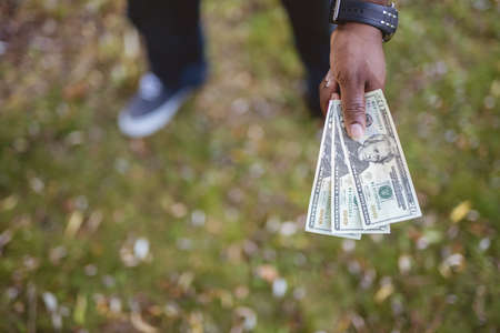 An overhead closeup shot of a male holding twenty dollar bills wit ha blurred background