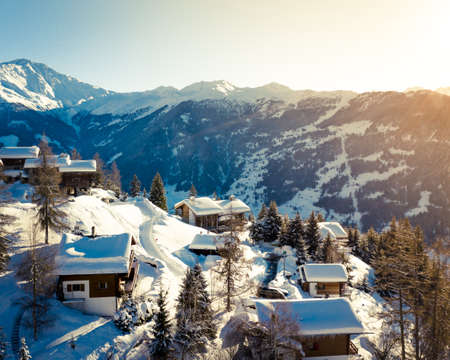 A beautiful bird's-eye shot of a town on a plateau surrounded by mountains covered in snow. Perfect for a wallpaper or a travel blog.の写真素材