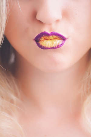 A closeup shot of a blonde female wearing a purple and yellow lipstick - great for a makeup blogの写真素材