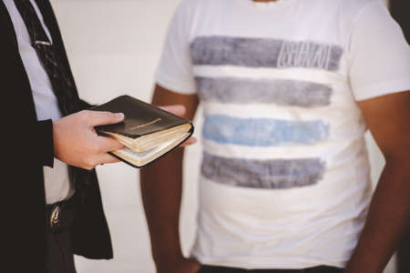 A closeup shot of a well dressed male holding the bible while talking to a personの写真素材