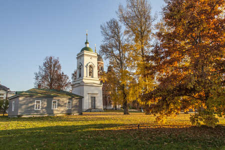 A horizontal shot of a white orthodox church in Borodino field, Russia surrounded by trees