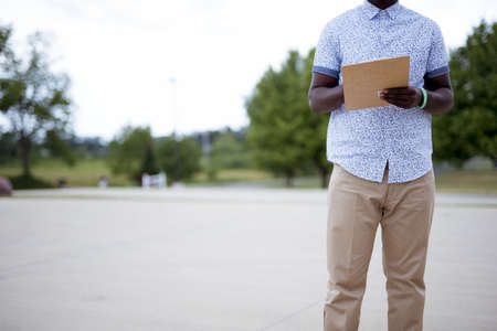 A closeup shot of a person writing on a clipboard with a blurred backgroundの写真素材