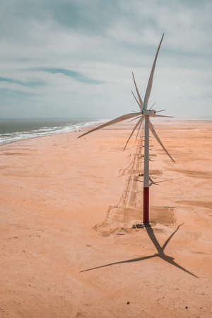 A vertical shot of a turbine on the beach by the sea under the cloudy sky