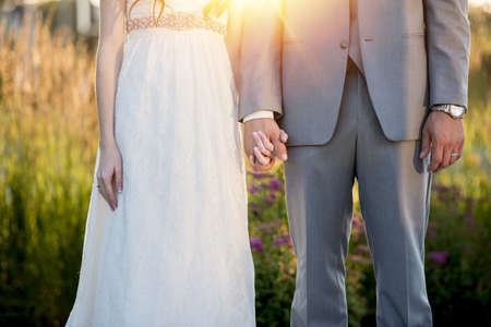 A beautiful shot of the bride and the groom holding hands with a blurred backgroundの写真素材