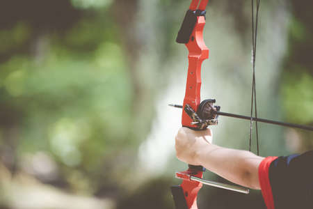 A closeup shot of a person holding a bow and arrow with a blurred backgroundの写真素材