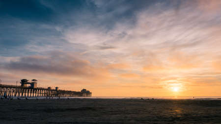 A landscape shot of a body of water with a pier in the distance during the beautiful sunset. Perfect for a wallpaper or a background.