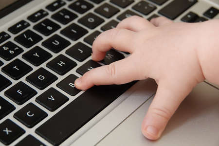 A closeup shot of a baby's hand on a computer keyboard