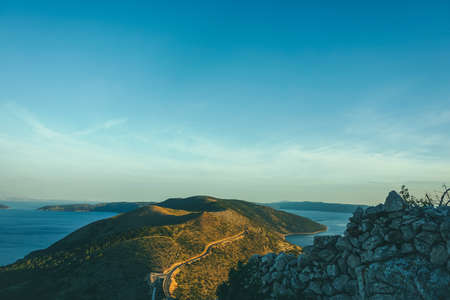 A high angle shot of a green grassy hill on the sea under the beautiful skyの写真素材