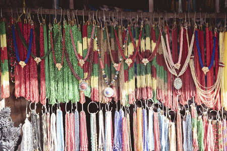 A closeup shot of hand made necklaces hanging on the shelf in the marketの写真素材