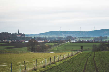 A high angle shot of a green landscape with a fence surrounded by high mountains under the cloudy...