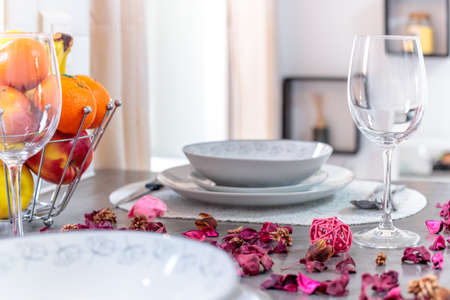 A selective focus shot of a modern table setting with flower petals, fruit and beautiful silverware