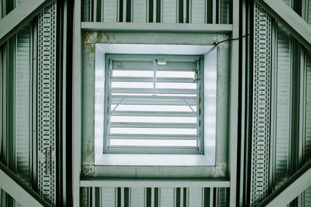 A half open white window on a patterned wall