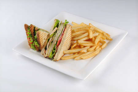 An isolated shot of a white plate with a club sandwich and french fries -  perfect for a food blog...