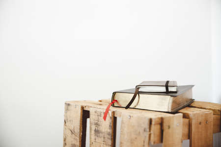 A closeup shot of a bible and notepad on a wooden box with a white backgroundの写真素材