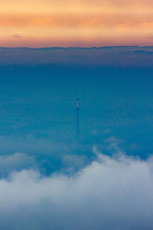 A vertical shot of a large chimney in Zagreb in the middle of the fog