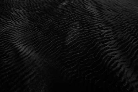 A closeup shot of wet black sand perfect for using a neutral backgroundの写真素材