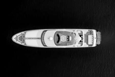 A high angle greyscale shot of a white luxury yacht on the sea surface