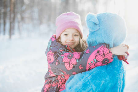 A closeup shot of a smiling little girl in the arms of a female in a fluffy blue costume