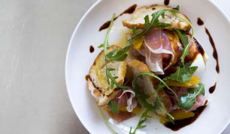 A high angle shot of a meat sandwich with vegetables in a white plate