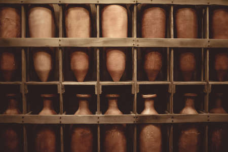 A wooden shelf filled with vintage ceramic vaseの写真素材
