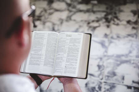 A selective focus shot of a person reading the bible with a blurred background