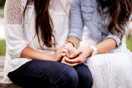 A closeup shot of female couples holding hands with a blurred backgroundの写真素材