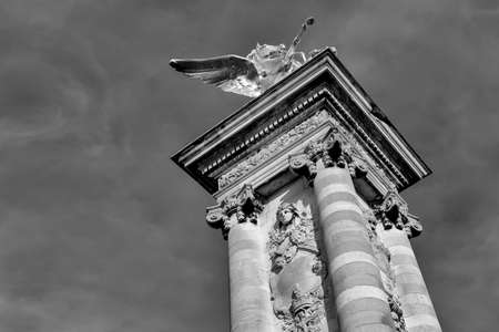 A grayscale low angle shot of a historical column with beautiful sculptures
