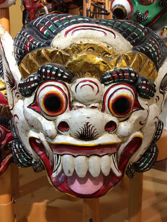 A vertical closeup shot of a scary colorful tribal mask with its teeth out and bulging eyesの写真素材