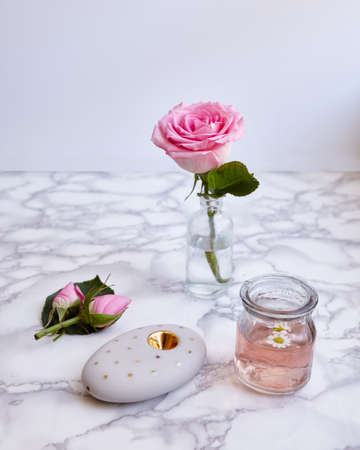 A vertical shot of a beautiful pink rose and floral objects on a surface with beautiful patterns