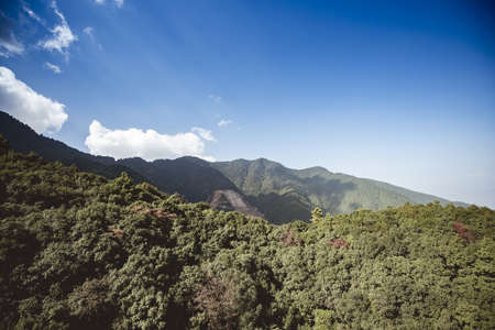 A beautiful shot of forested mountains under a blue sky in Nepal