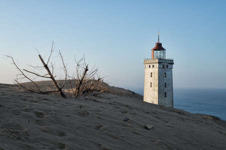 A low angle shot of a lighthouse standing on top of a hill during sunsetの写真素材