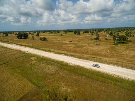 An aerial shot of a road surrounded by grass covered fields captured in Zanzibar, Africa
