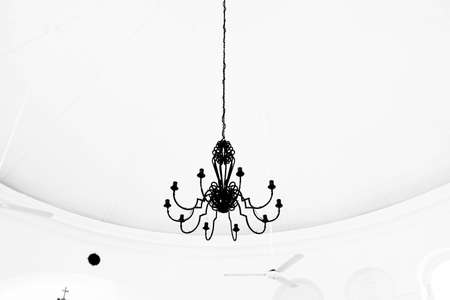 A low angle shot of a black chandelier hanging in a white roomの写真素材