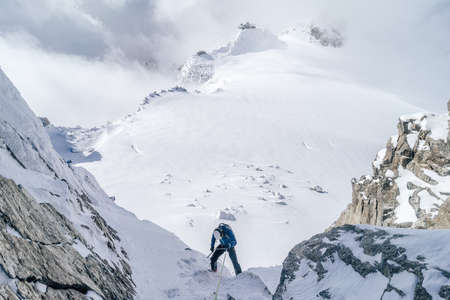 A mountain climber climbing the snow covered Alps in Mont Blanc Massifの写真素材