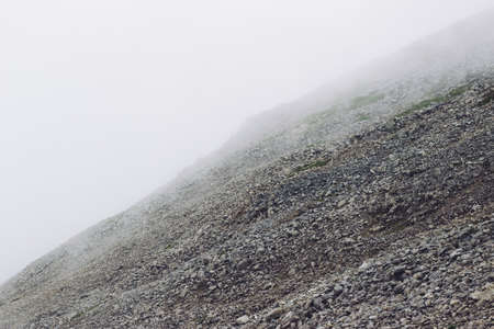 A low angle shot of smoke coming out of the mountains in the middle of a green scenery