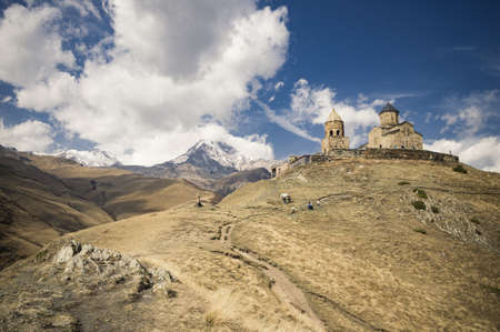 A low angle shot of historic Trinity Church in Gergeti, Georgia under the beautiful cloudy sky