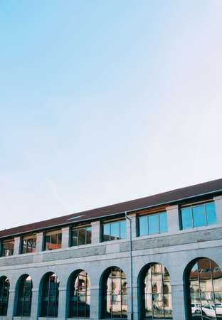 A vertical low angle shot of a concrete building with reflective windows under the clear skyの写真素材