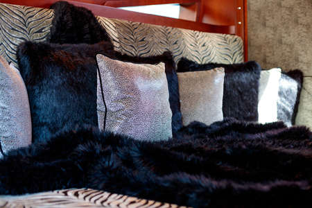A closeup shot of many fluffy pillows and a blanket on the bed