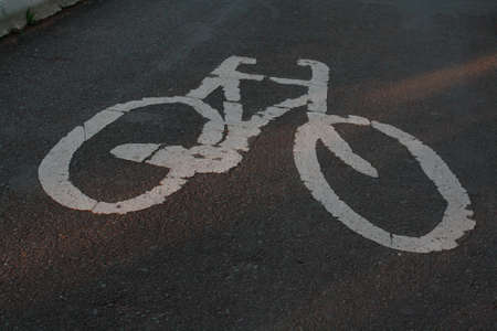 A high angle shot of a white bicycle sign painted on an asphalt road. Perfect for road sign usage.