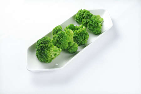 An isolated shot of a white plate with fresh broccoli - perfect for a recipe article  or menu usage