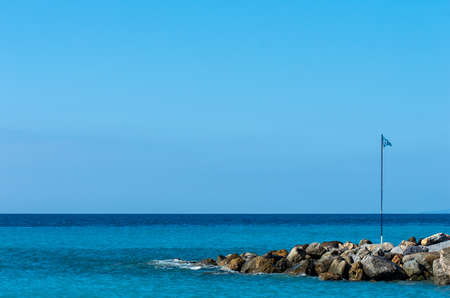 A pile of rocks near the beautiful calm sea under the blue skyの写真素材