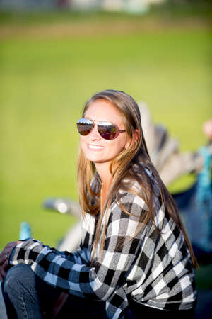 A vertical shot of a female wearing sunglasses and smiling at the cameraの写真素材