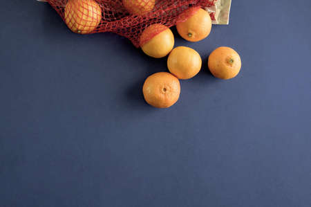 An overhead shot of oranges spilled out of the bag on a dark blue surfaceの写真素材