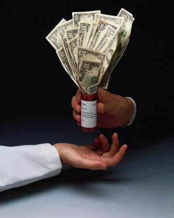 A vertical closeup shot of a person giving a bunch of dollars to a doctor - corruption in medicine conceptの写真素材