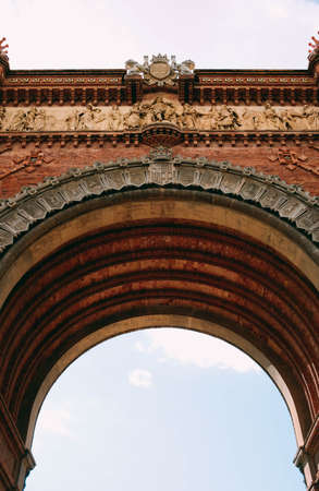 A vertical low angle shot of a concrete arch with beautiful carvingsの写真素材