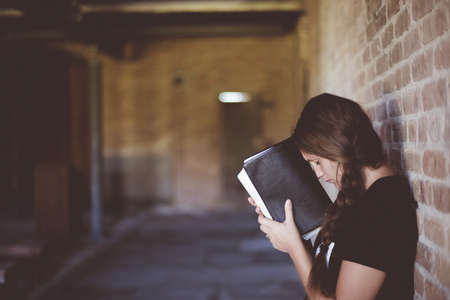 A closeup shot of a female with the bible against her head while praying with a blurred backgroundの写真素材