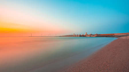 The breathtaking view of the sunset over the calm ocean captured in Zeeland, Netherlandsの写真素材