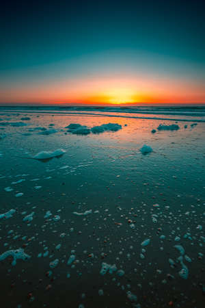 A vertical shot of the beautiful sunset over the sea captured in Domburg, Netherlandsの写真素材